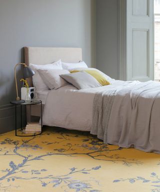 Bedroom carpet ideas with bold yellow and blue floral patterned carpet, with pale blue-grey walls