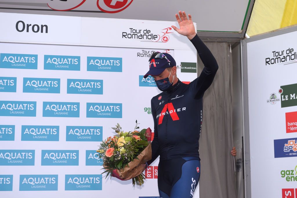 Rohan Dennis (Ineos Grenadiers) steps onto the Tour de Romandie podium after winning the prologue