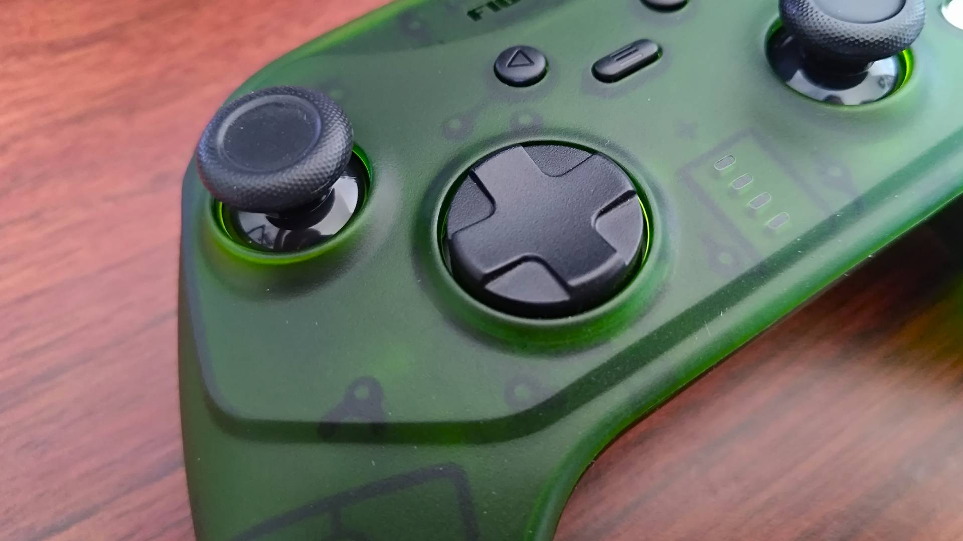 Close up of Retro Fighters Hunter left thumbstick and d-pad on woodgrain desk.