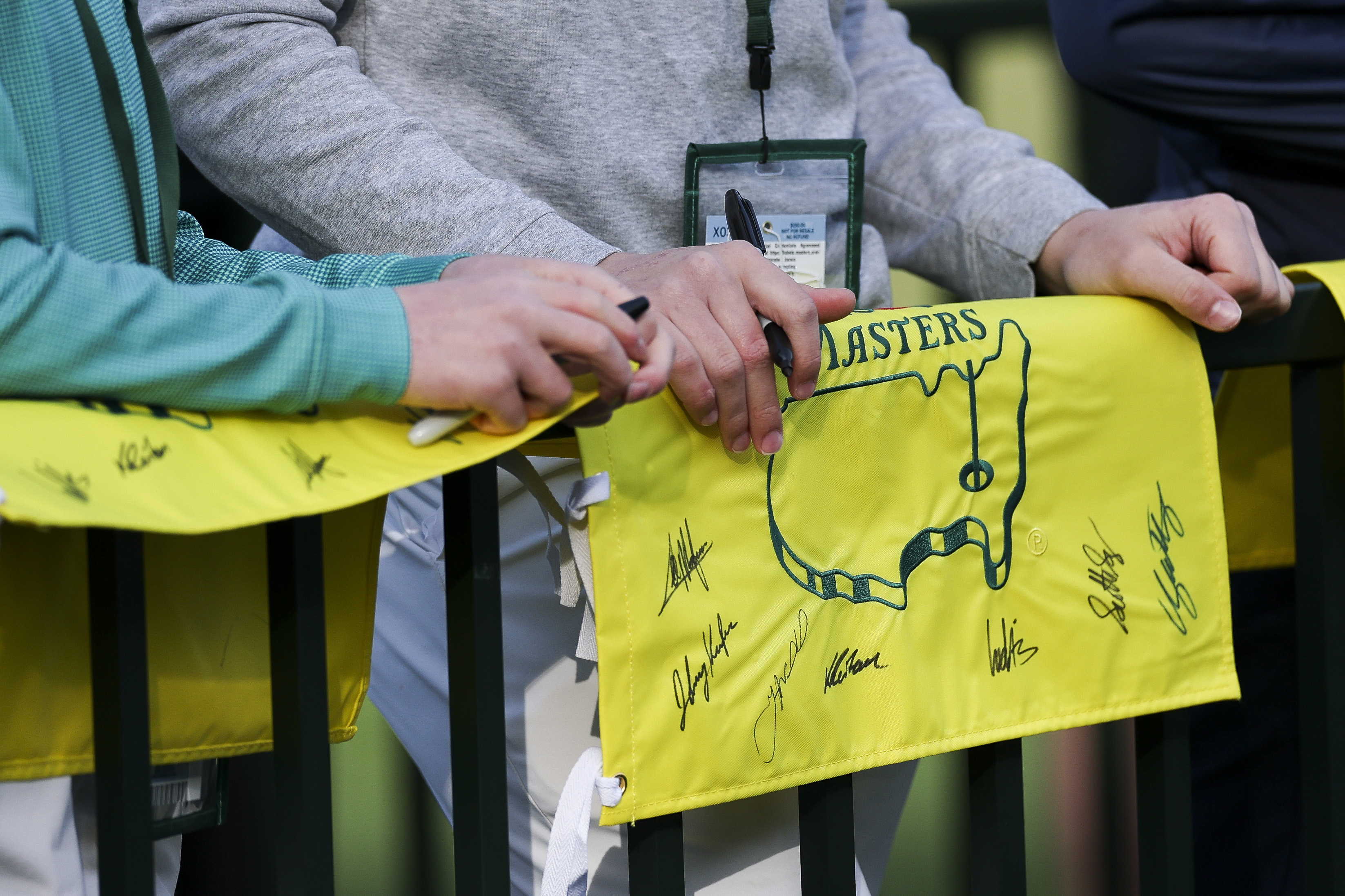 A detailed view of patrons holding autographed flags is seen during a practice round prior to the 2026 Masters Tournament at Augusta National Golf Club