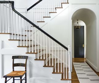staircase with white walls and old chair
