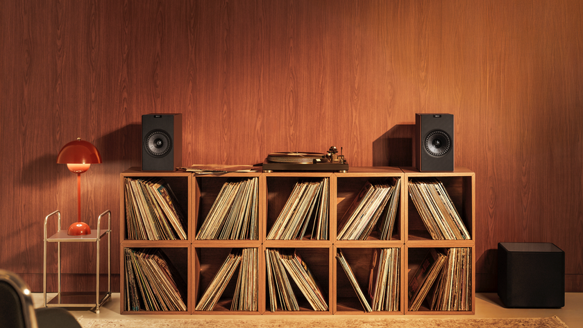 KEF Coda W speakers on top of a vinyl storage unit in a very 70s-looking room