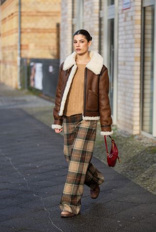 woman wearing shearling jacket, sweater, plaid pants, and boots