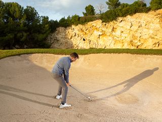 Golf Monthly Top 50 Coach Dan Grieve demonstrating correct set up position with a 5-iron for a practice drill in the greenside bunker