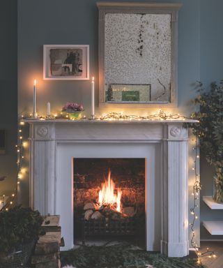 Christmas fireplace decorated with string lights and an antique mirror