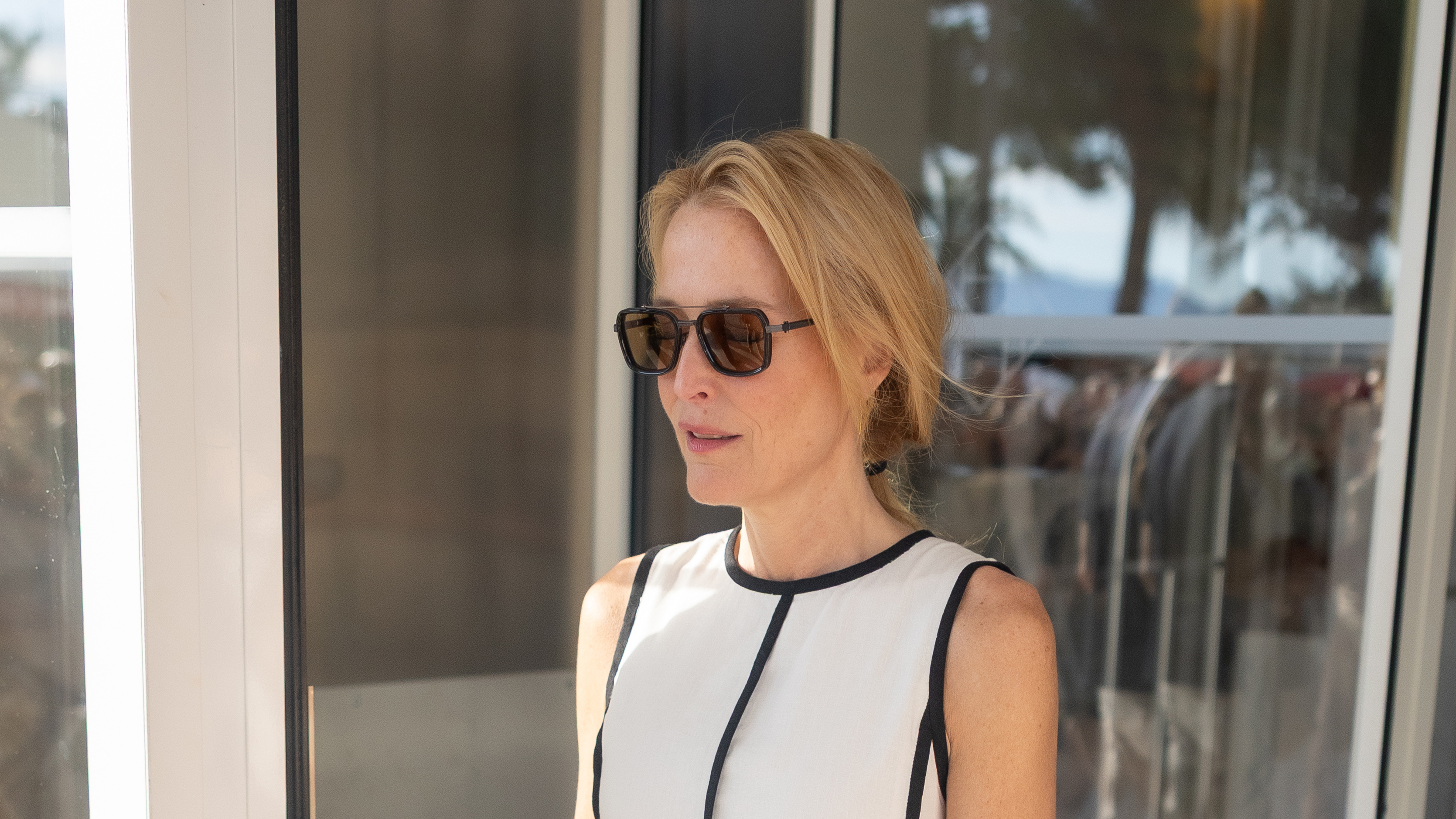 Gillian Anderson wearing a cream and black dress and black sunglasses