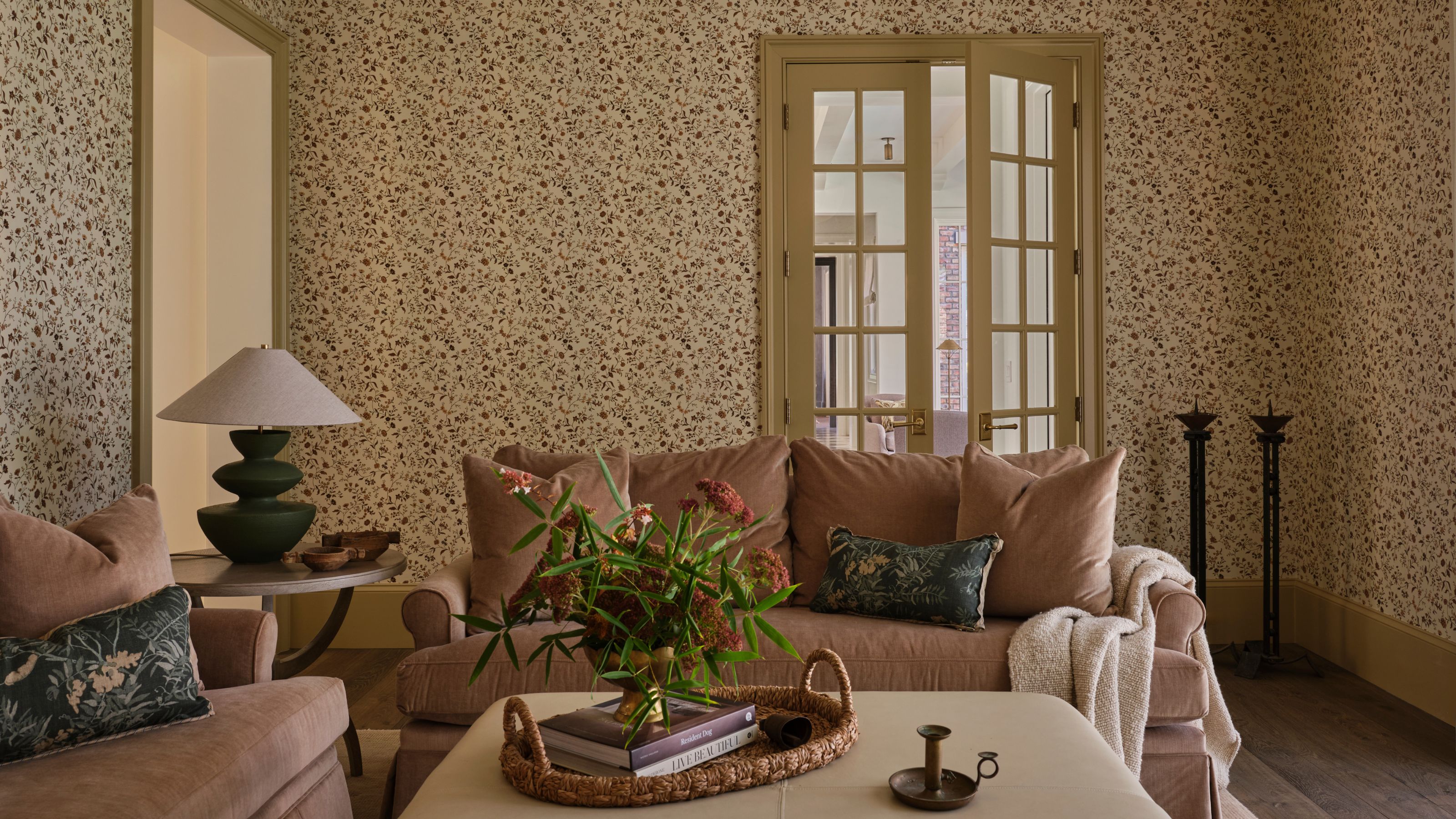 a cozy yellow painted ditsy floral wallpapered lounge with soft pink velvet couches and layered vintage pieces