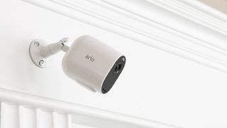 Arlo Essential Spotlight Camera monterad på vit vägg.