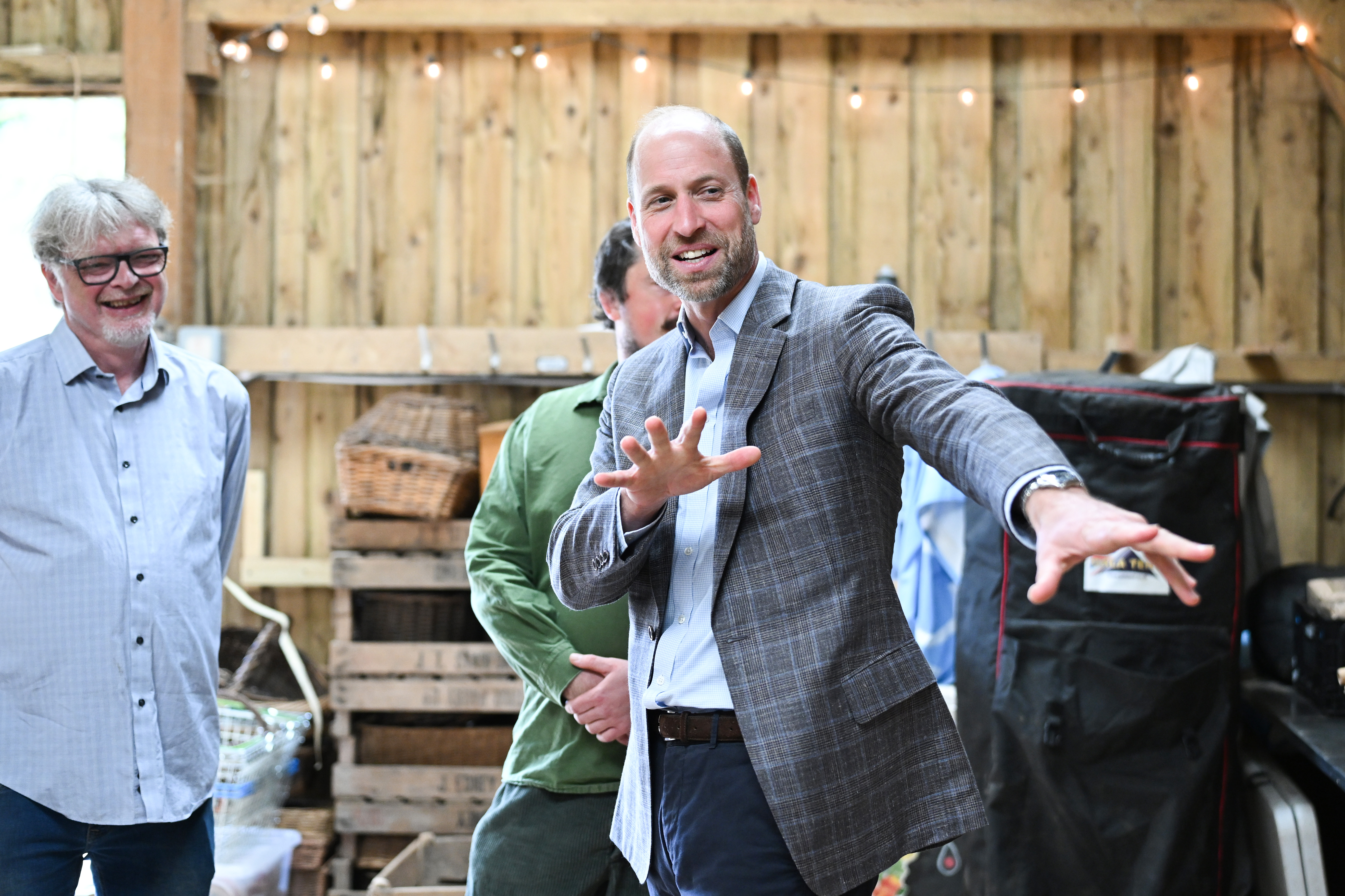 Prince William wears a gray plaid suit with a blue shirt and jeans while visiting the Apricot Centre, a carbon-negative farm and wellbeing service on June 18, 2026 in Totnes, England