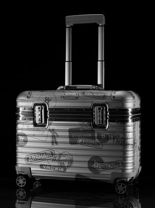 A hardshell suitcase covered in labels from the brand.