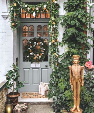 Festive doorscape with fresh greenery and DIY decorated wreath with baubles and dried orange slices