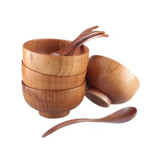 Four warm colored wooden bowls with spoons inside them and one spoon next to them