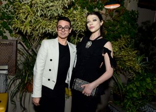 Michelle Trachtenberg wearing a black dress posing in front of a large plant with Christian Siriano at a 2023 party