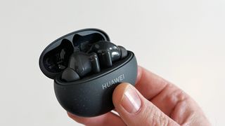 Mustat Huawei Freebuds 5i -nappikuulokkeet mustassa latauskotelossa ihmisen kädessä
