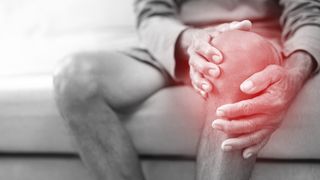 A black and white photo of an older man clutching his knee, with a red glow around his knee indicating pain