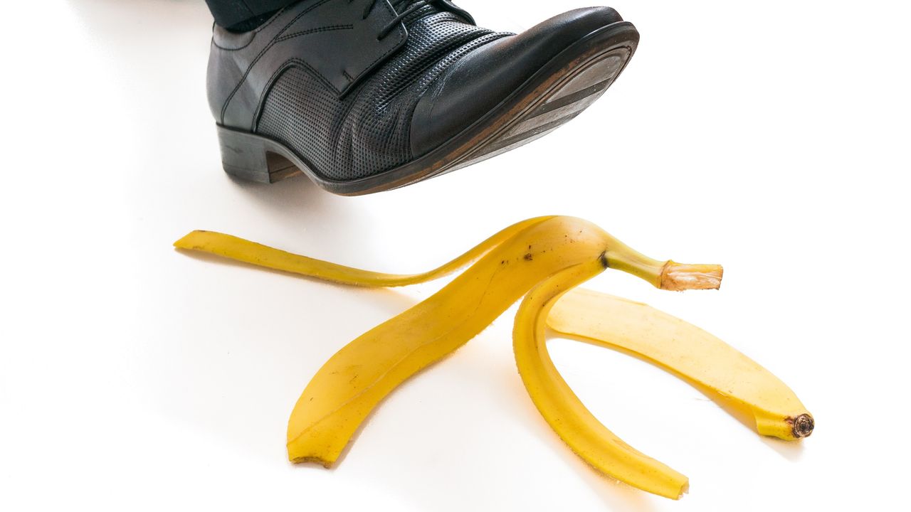 A businessman&#039;s foot is about to step on a banana peel.