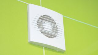 white bathroom extractor fan set in wall with bright green tiles