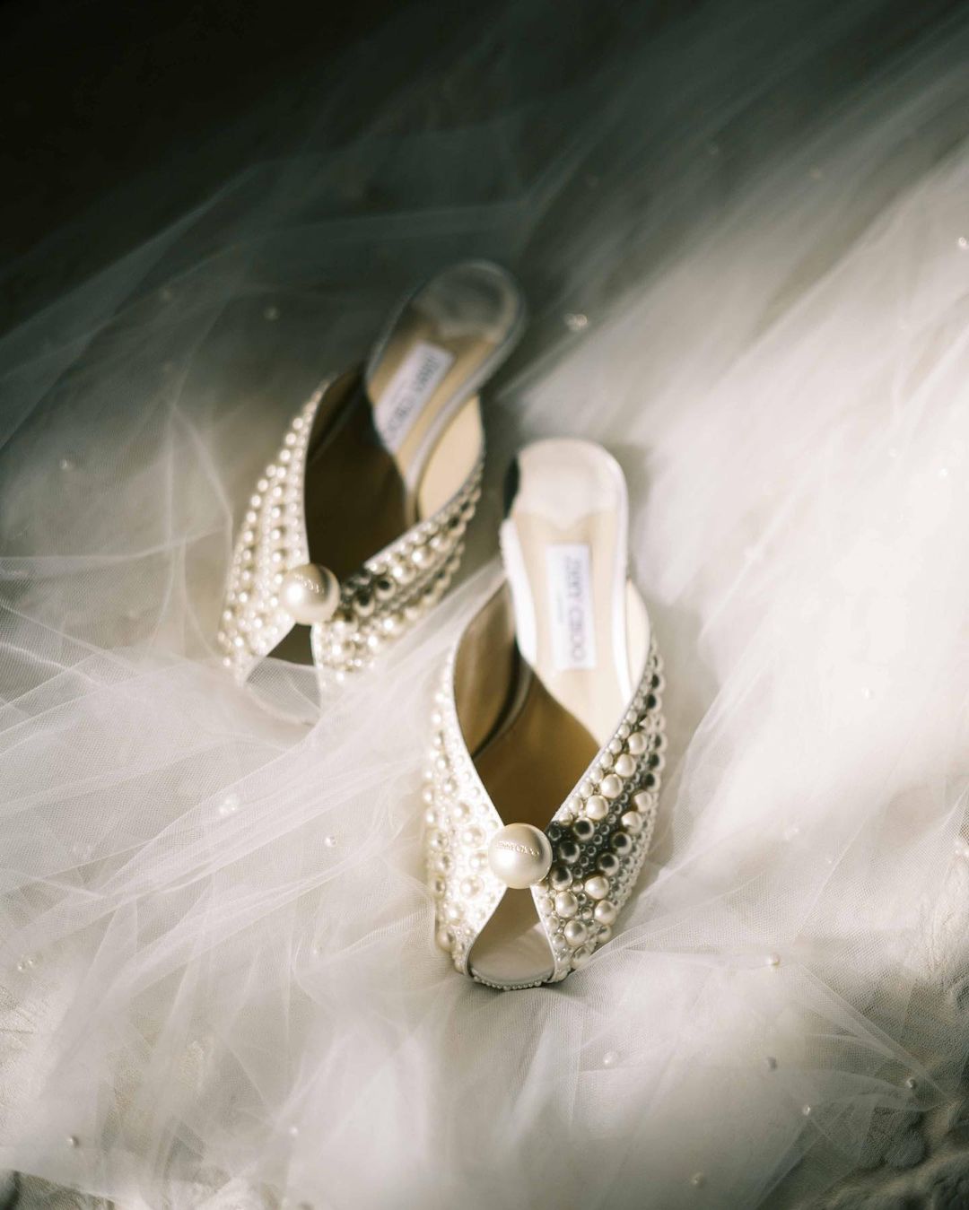 Image of pearl Jimmy Choo shoes on top of a bridal veil