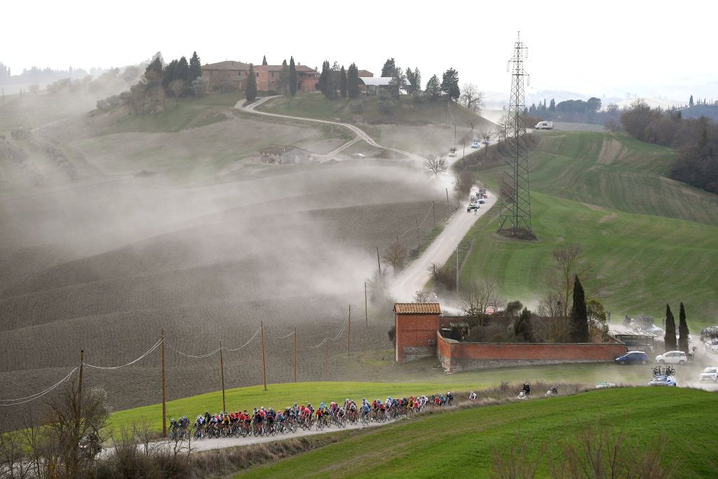 SIENA ITALY MARCH 05 The peloton passing through a dusty gravel strokes sector during the Eroica 16th Strade Bianche 2022 Mens Elite a 184km one day race from Siena to Siena Piazza del Campo 321m StradeBianche WorldTour on March 05 2022 in Siena Italy Photo by Tim de WaeleGetty Images
