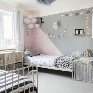 Pink, grey and white kids room with fairy lights, wall decor and twin beds