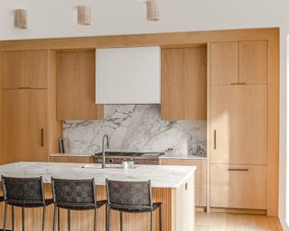 Kitchen with natural toned wood cabinets and island and veined backsplash