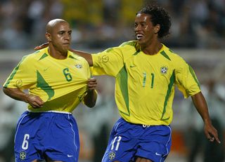 SEOGWIPO, REPUBLIC OF KOREA: Brazil's Roberto Carlos (L) is congratulated by teammate Ronaldinho after scoring off a free-kick in the 14th minute, 08 June 2002 at the Jeju World Cup Stadium in Seogwipo, during first round Group C action between Brazil and China in the 2002 FIFA World Cup Korea/Japan. AFP PHOTO/GREG WOOD (Photo credit should read GREG WOOD/AFP via Getty Images)