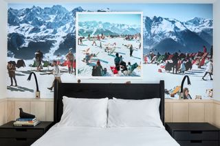 A black headboard is backed by a mural of a ski scene