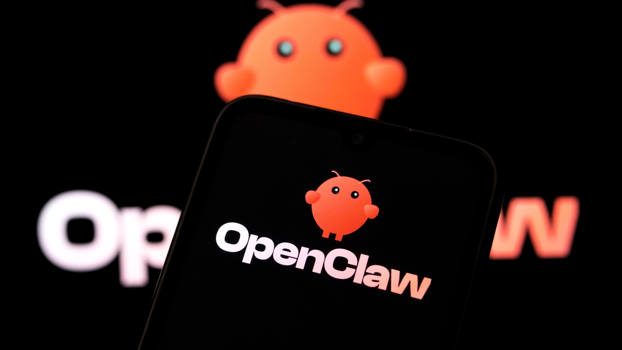 The OpenClaw logo appears on a smartphone screen and as the background on a laptop computer screen.