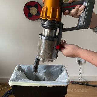 Emptying a Dyson vacuum into a bin with a white bin bag