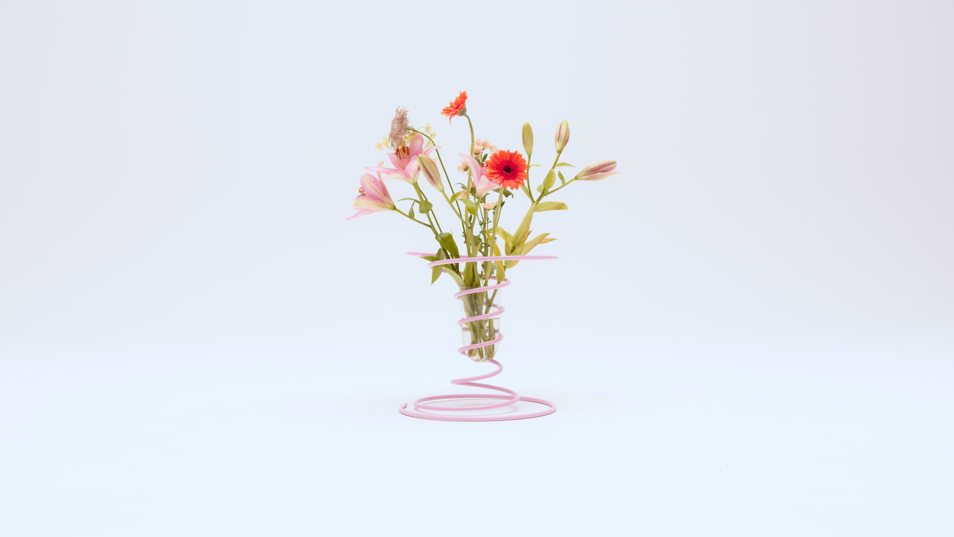 flowers arranged in a glass vase in a spring-like metal spiral frame
