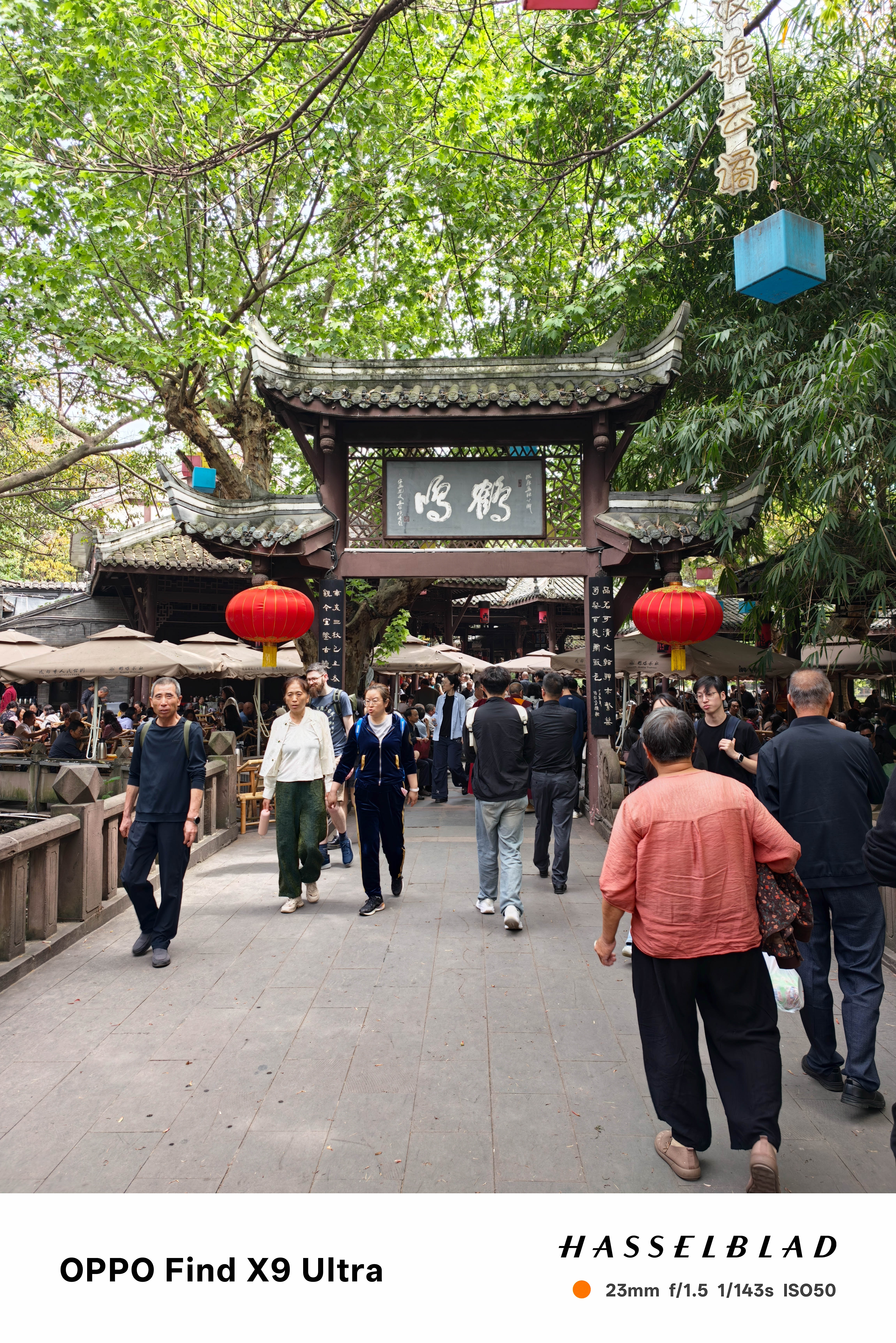 Crowded traditional market entrance with red lanterns and people walking through