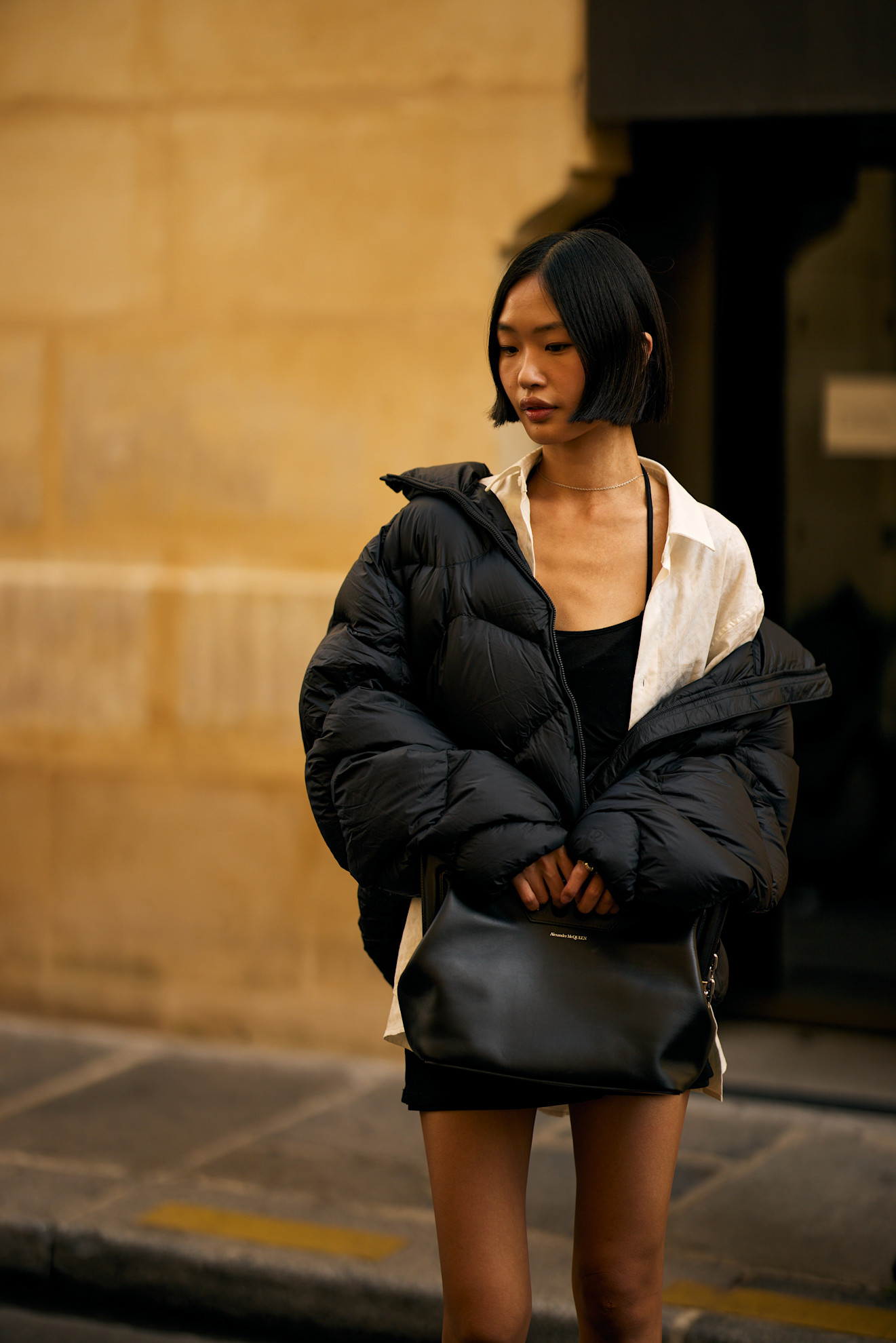 an asian woman with a short black bob in a black puffer coat and black dress