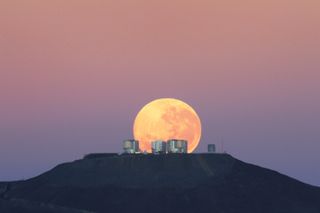 The full moon looks massive as it sets behind the Very Large Telescope in Chile's Atacama Desert, in this photo release on Jun 7, 2010. Why do observers report that the moon looks larger near the horizon than it does high in the sky? It may be nothing more than a trick of perspective. 