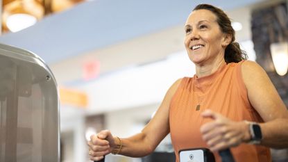 Woman using low row machine in the gym, smiling, representing one type of heavy strength training done in the study