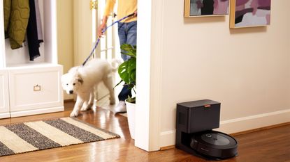 An iRobot Roomba j7+ with man and dog in hallway