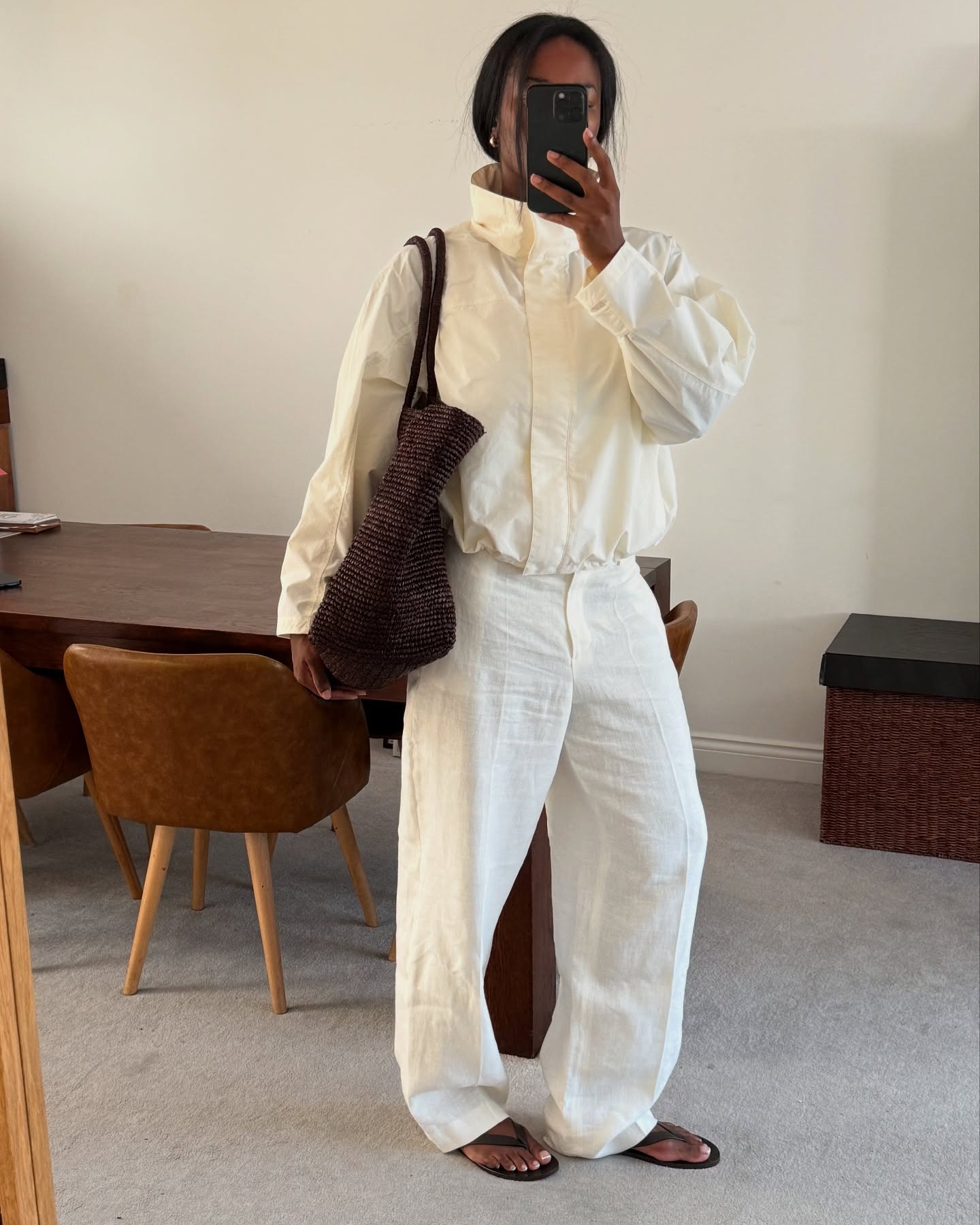 Marilyn wears a white sporty jacket, white linen pants and flip flops.