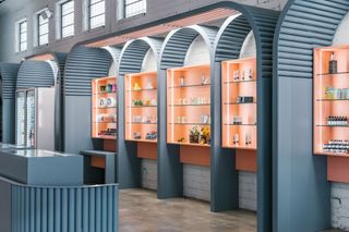 Orange wall shelves surrounded by grey panels which are arched on the tops.