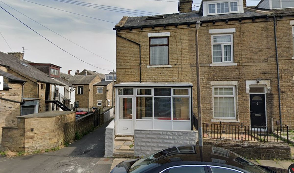 A front view of the yellow brick terraced property with the white single storey extension visible 