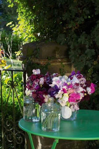 green metal table with flowers for sale on it