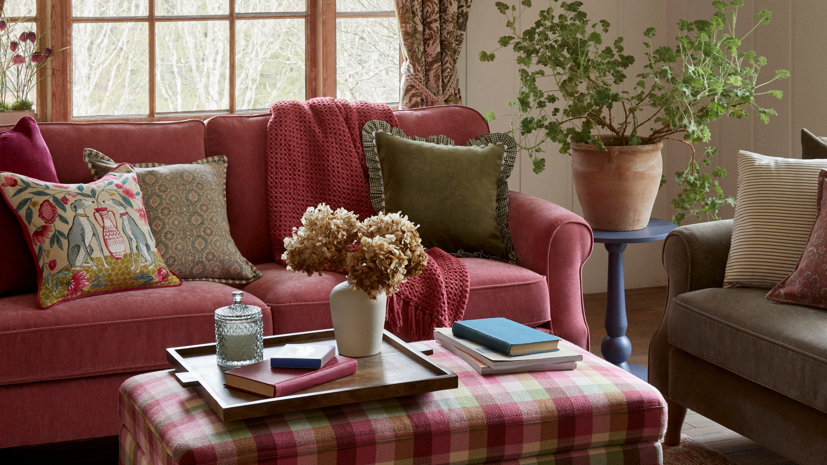 Dunelm check coffee table, pink sofa and blue side table holding potted plant. On the check table there is a tray and a bunch of dried hydrangeas.
