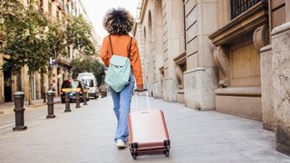 Summer scams - Woman walking with suitcase on holiday