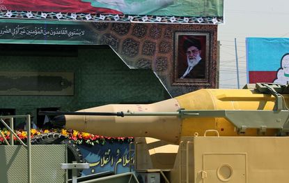 An Iranian missile passes in front of a photo of the ayatollah