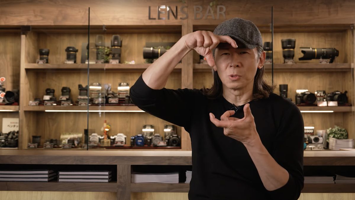 Takeo Suzuki of the Pentax Film Project, in front of a cabinet of cameras