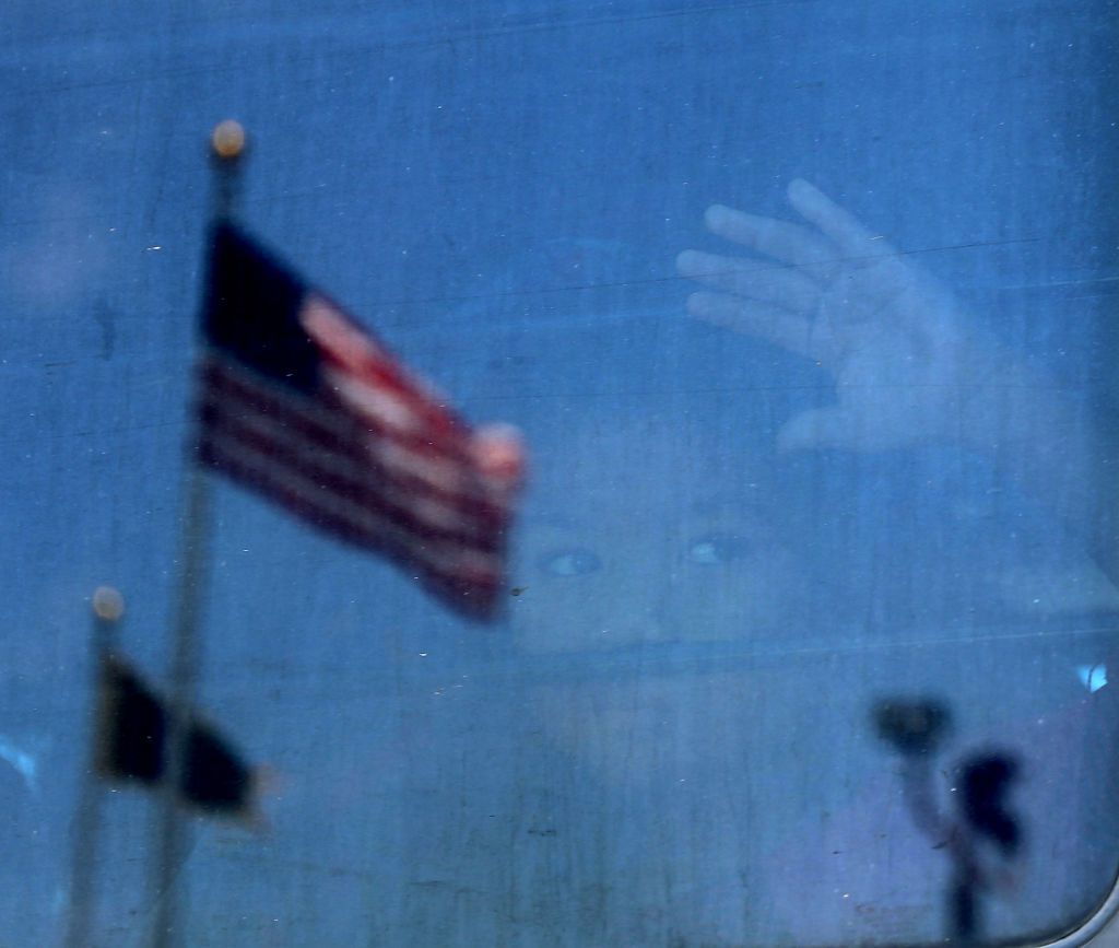 A migrant child looks outside a bus window.