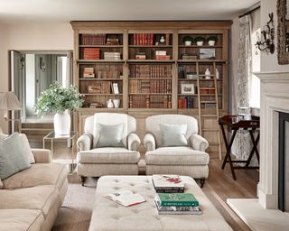 Formal living room ideas with cream traditional armchairs and wooden bookshelves