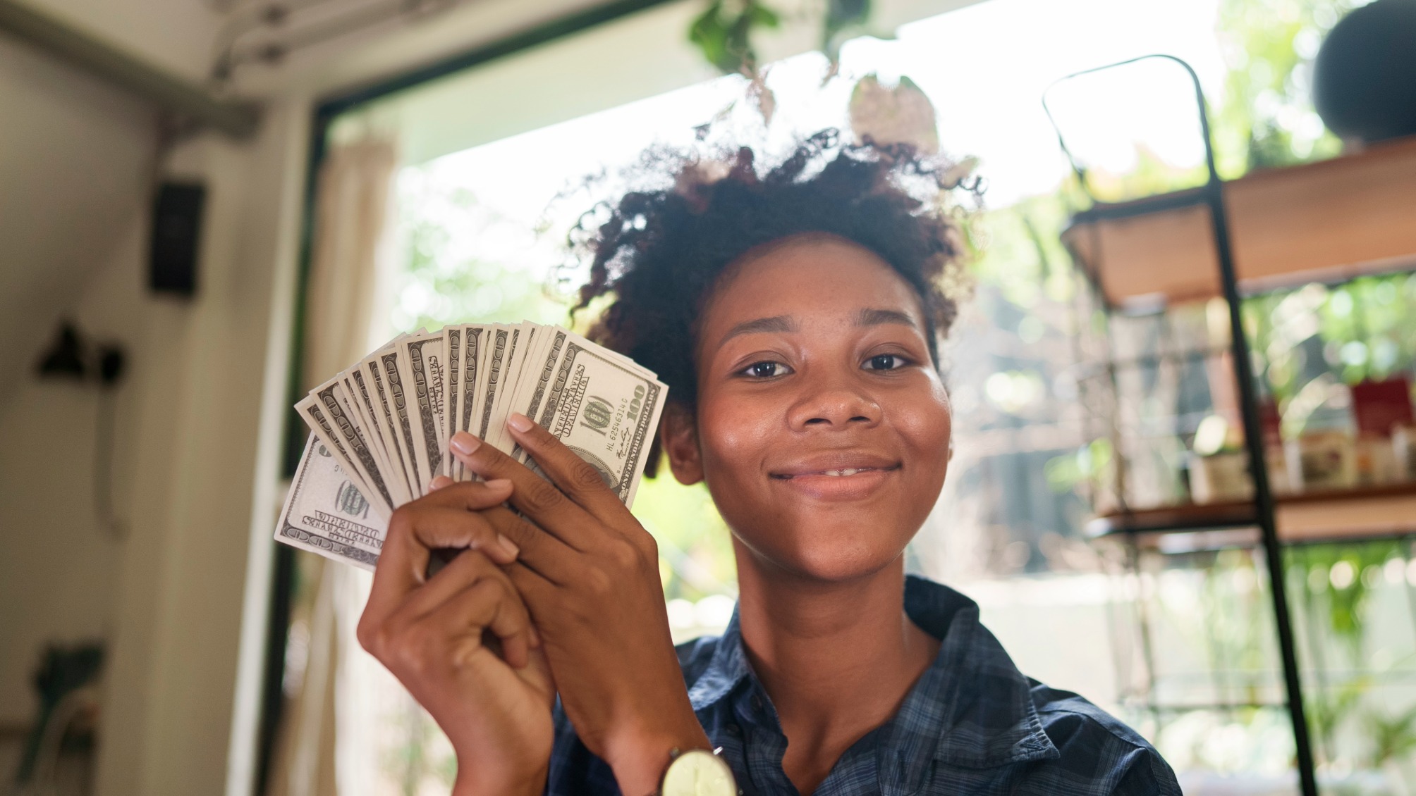 Happy young woman holding hundred dollar bills in a fan