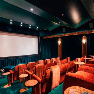 cinema room with velvet chair and wide screen