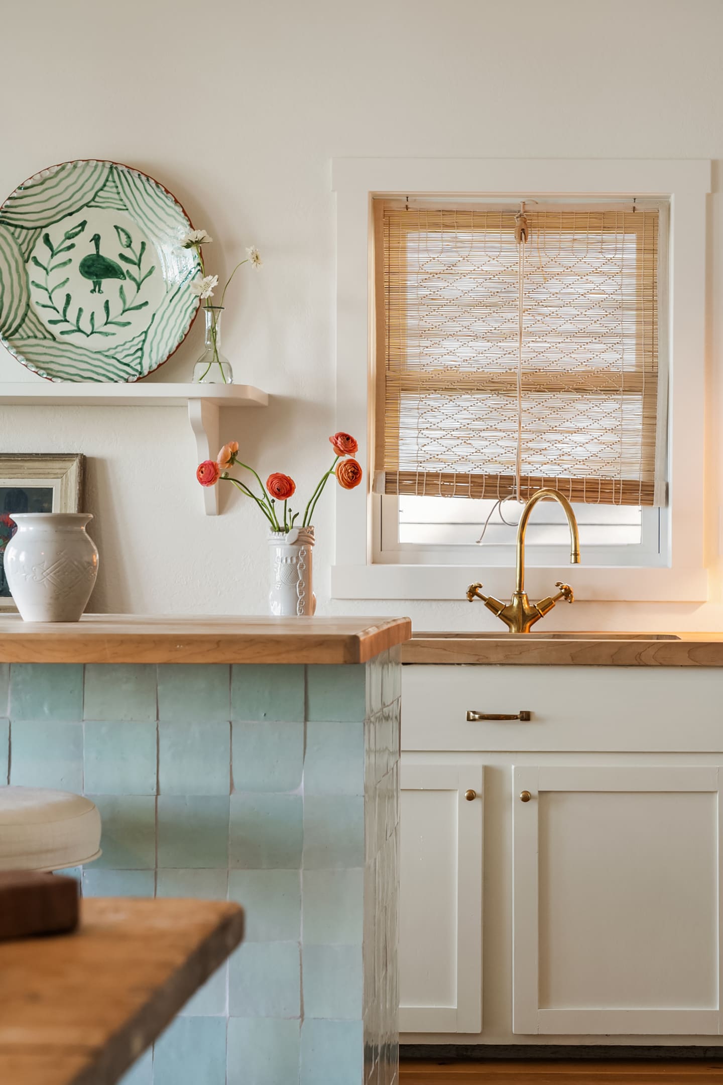 White kitchen with pale blue Zellige tiles and woven roller blind