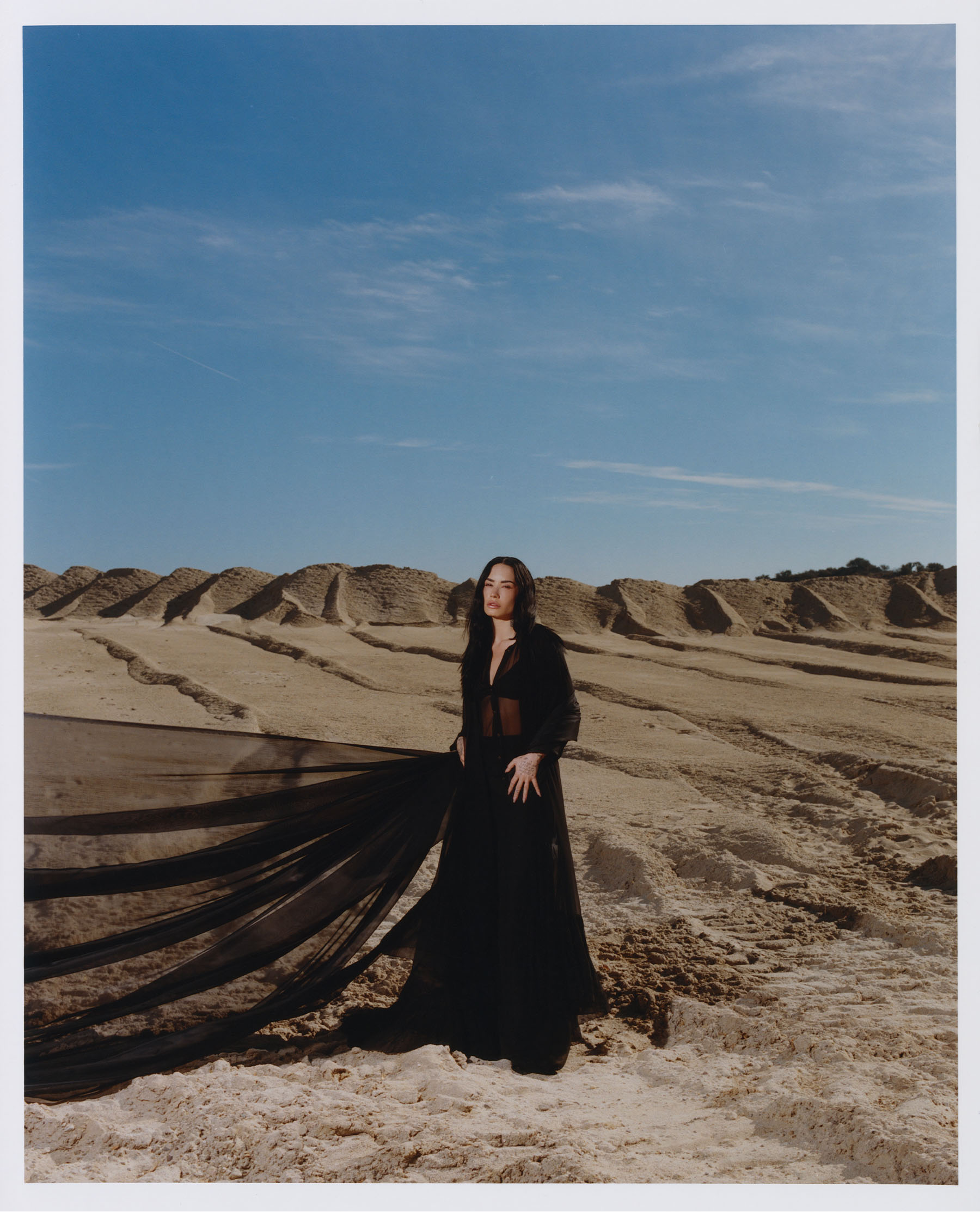 Demi Lovato forBest Knockoff Luxury Clothing
&#039;s November cover. Lovato is standing in the middle of a sand dune wearing a black maxi dress. The fabric is flowing off to the side.
