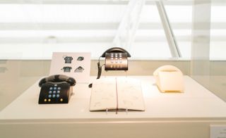 Black push button telephone alongside prototypes and renderings